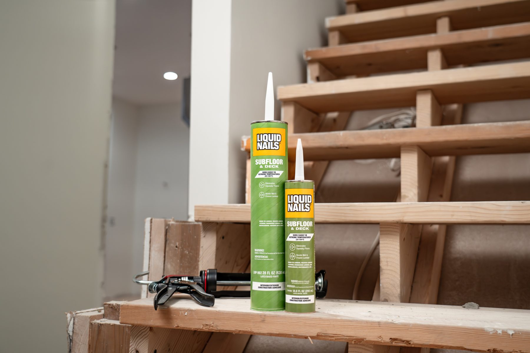 Liquid Nails Subfloor & Deck adhesive cartridges and caulk gun on stair stringers